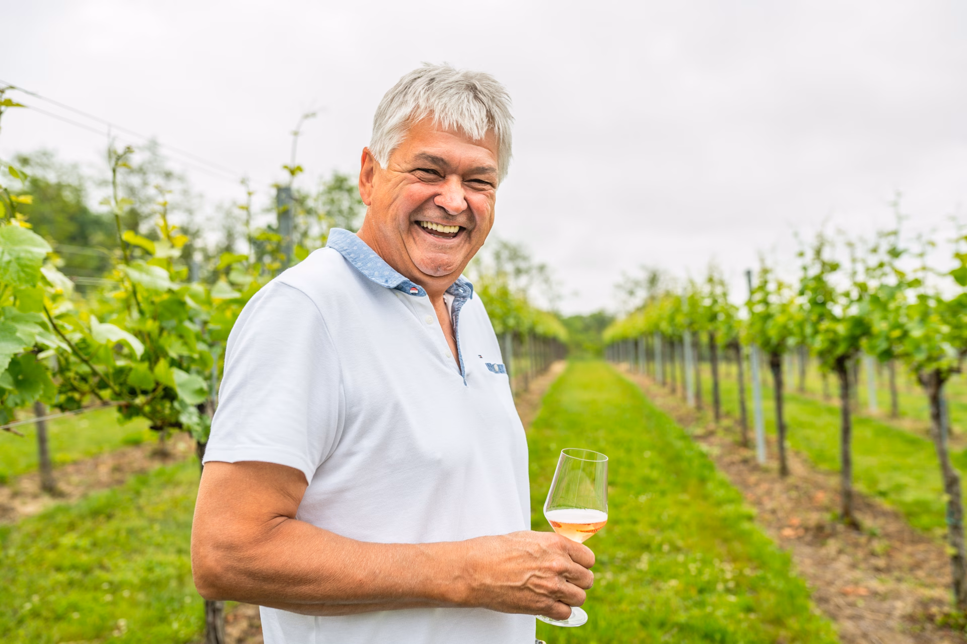 Lachender Mann der ein Glas Wein in der Hand hält